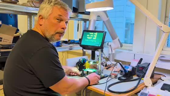 Einar inspecting a circuit board bearing the Spec-Imaging logo
