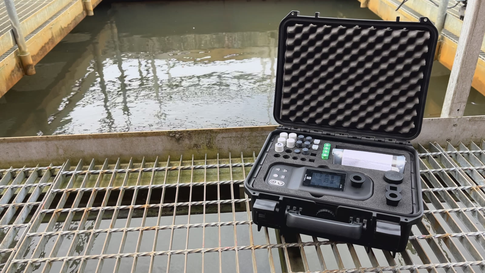 IC-VIS™ carrying case open at a wastewater treatment plant, with reagent vials and the handheld instrument beside the process water