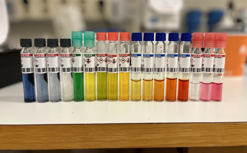 A row of Hach LCK reagent test-kit cuvettes in a range of colors, from blue and green through yellow, orange and pink, representing different colorimetric methods